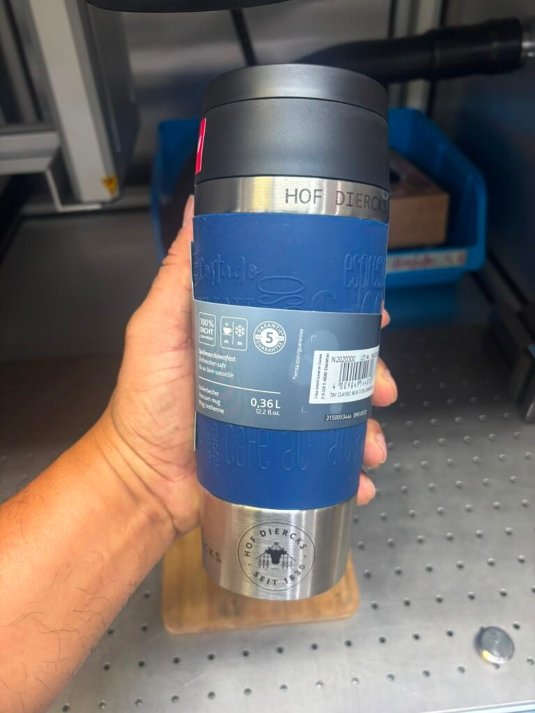 Thermobecher mit Lasergravur: Hof-Logo auf einem Emsa Travel Mug mit blauer Manschette